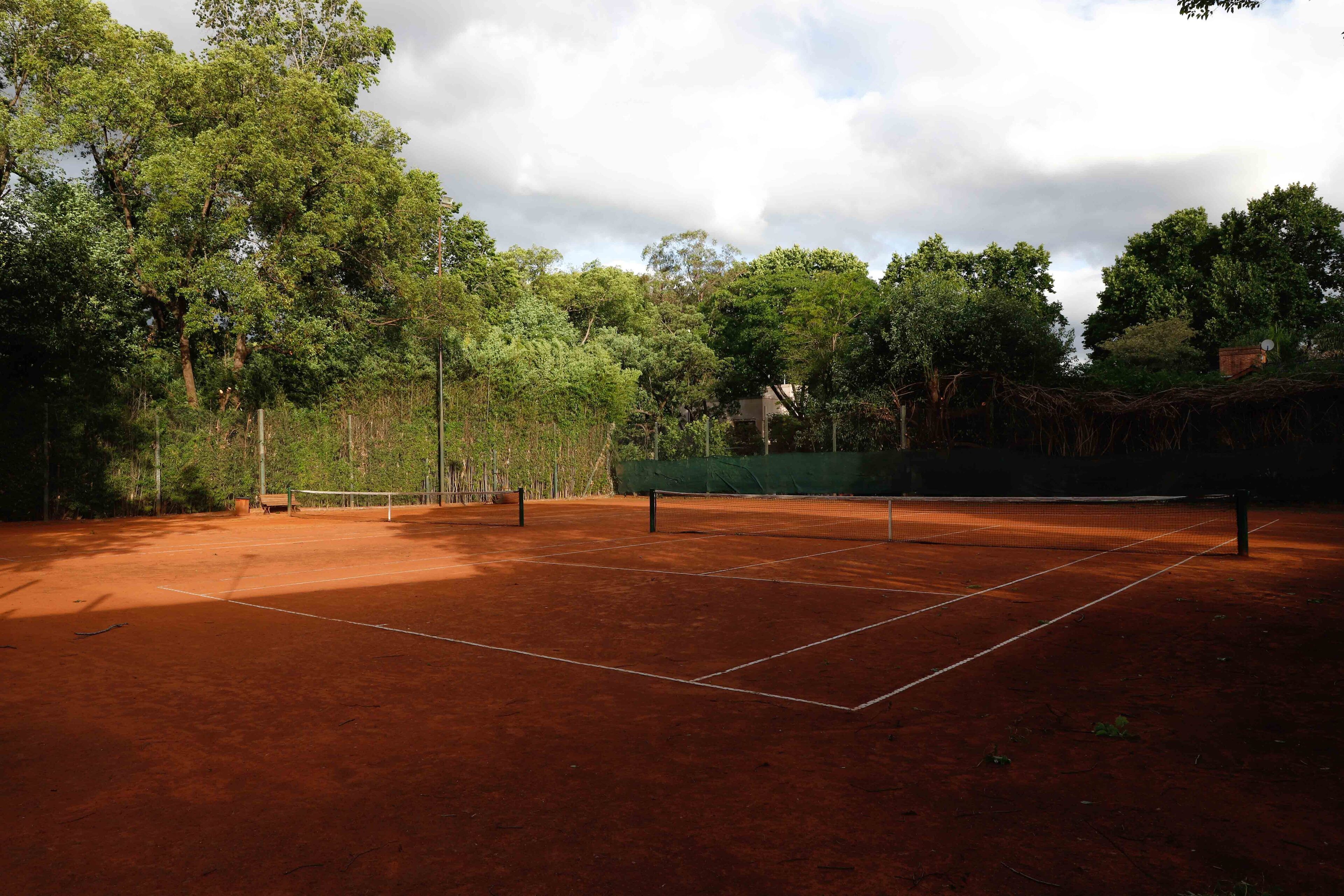 Una cancha de tenis al aire libre rodeada de árboles.