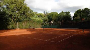 Una cancha de tenis al aire libre rodeada de árboles.