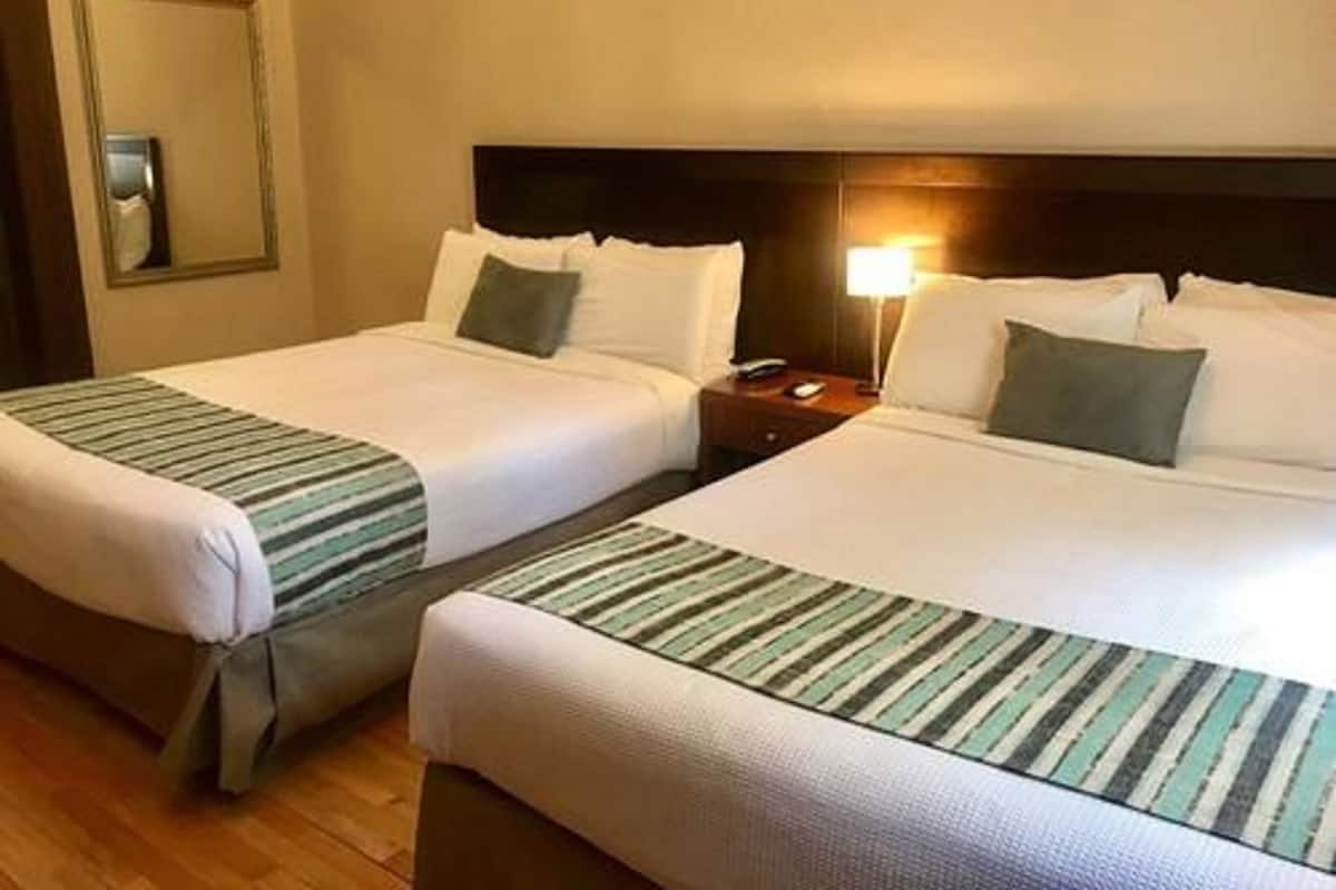 Two twin beds with striped bedding, a nightstand with a lamp, and a mirror on the wall.
