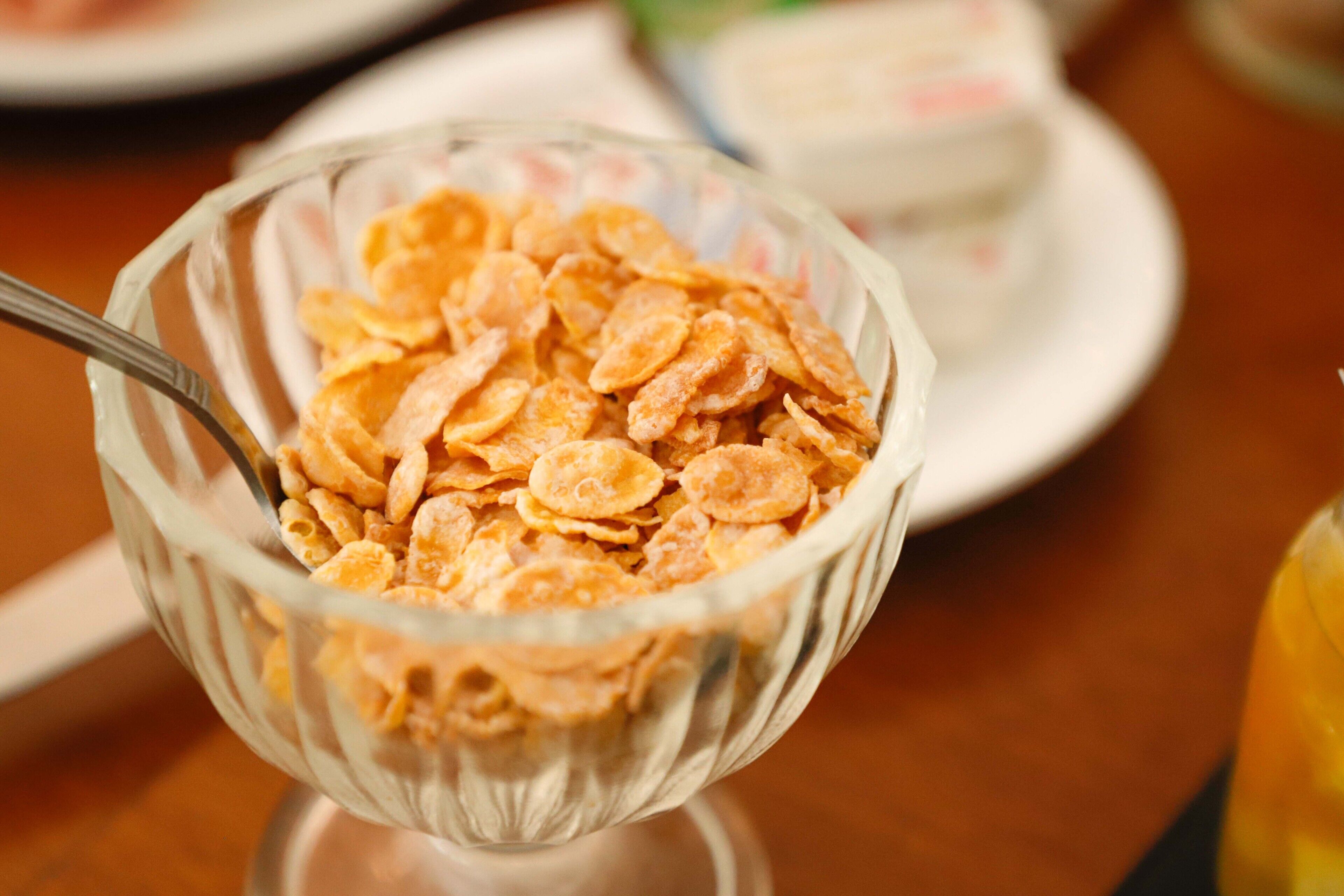 Un tazón de vidrio transparente lleno de copos de cereales sobre una mesa.