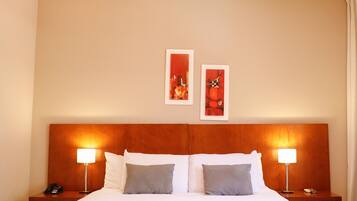 Una habitación de hotel con una cama grande, dos lámparas de noche y dos cuadros en la pared.