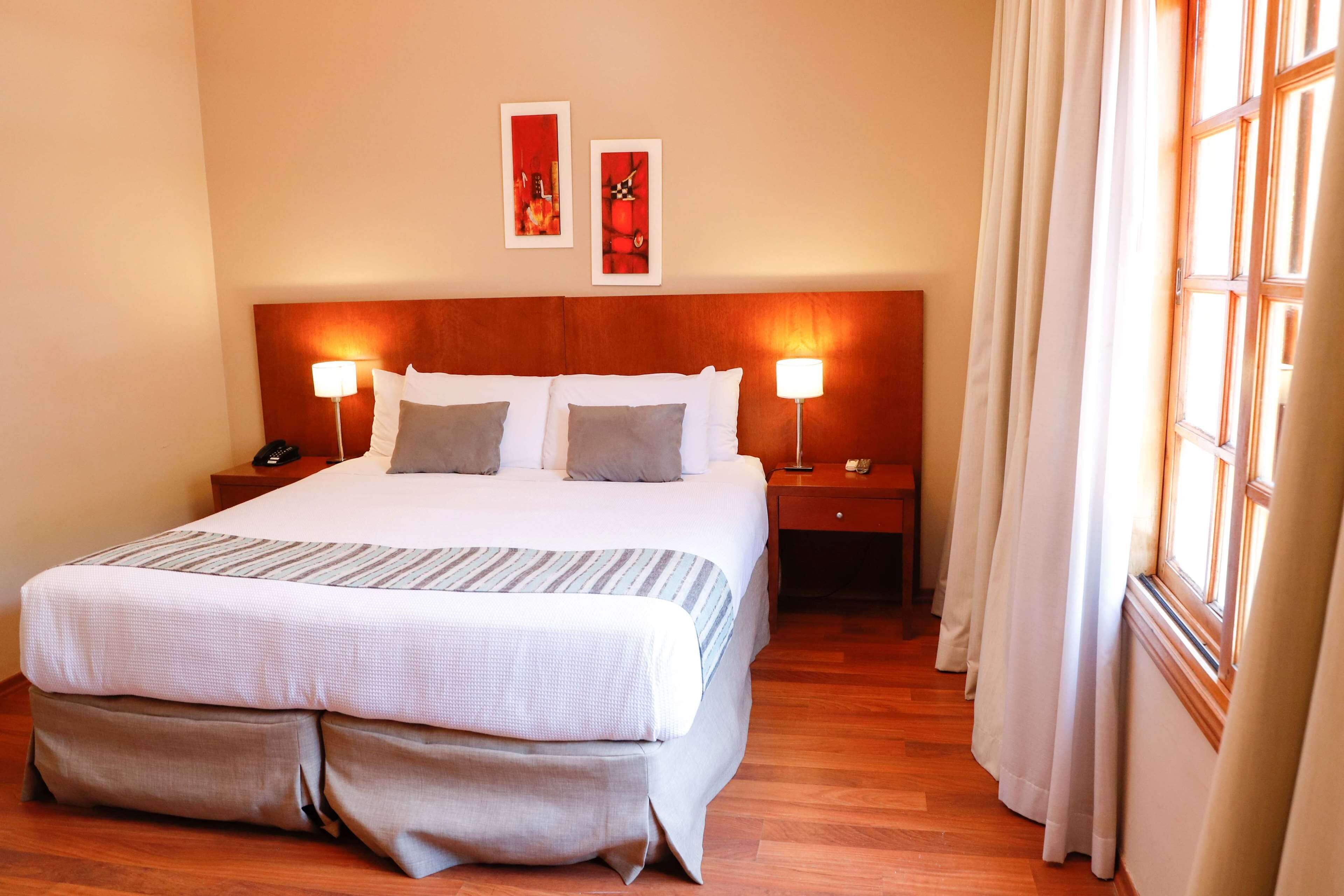 A neatly made bed with a striped bedspread, two bedside lamps, and a nightstand with a phone.