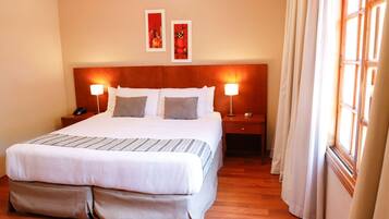 A neatly made bed with a striped bedspread, two bedside lamps, and a nightstand with a phone.