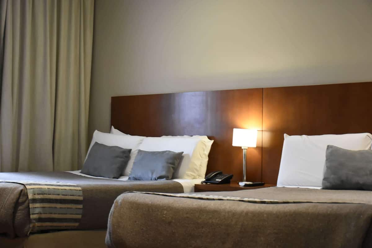 A hotel room with a large bed, two bedside tables, a lamp, and a telephone.