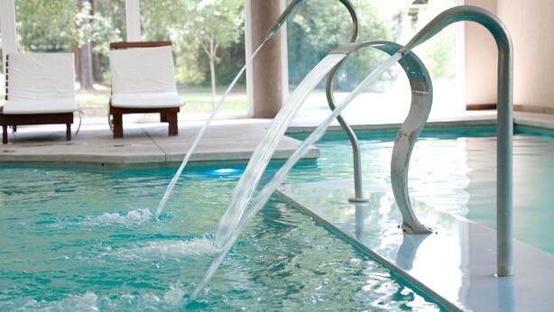 A swimming pool with clear water, two lounge chairs, and a view of trees and a building in the background. - Howard Johnson by Wyndham Escobar Hotel (Belen de Escobar)