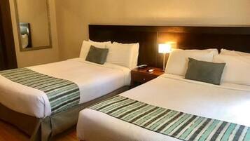 Two twin beds with striped bedding, a wooden headboard, a nightstand with a lamp, and a mirror on the wall.