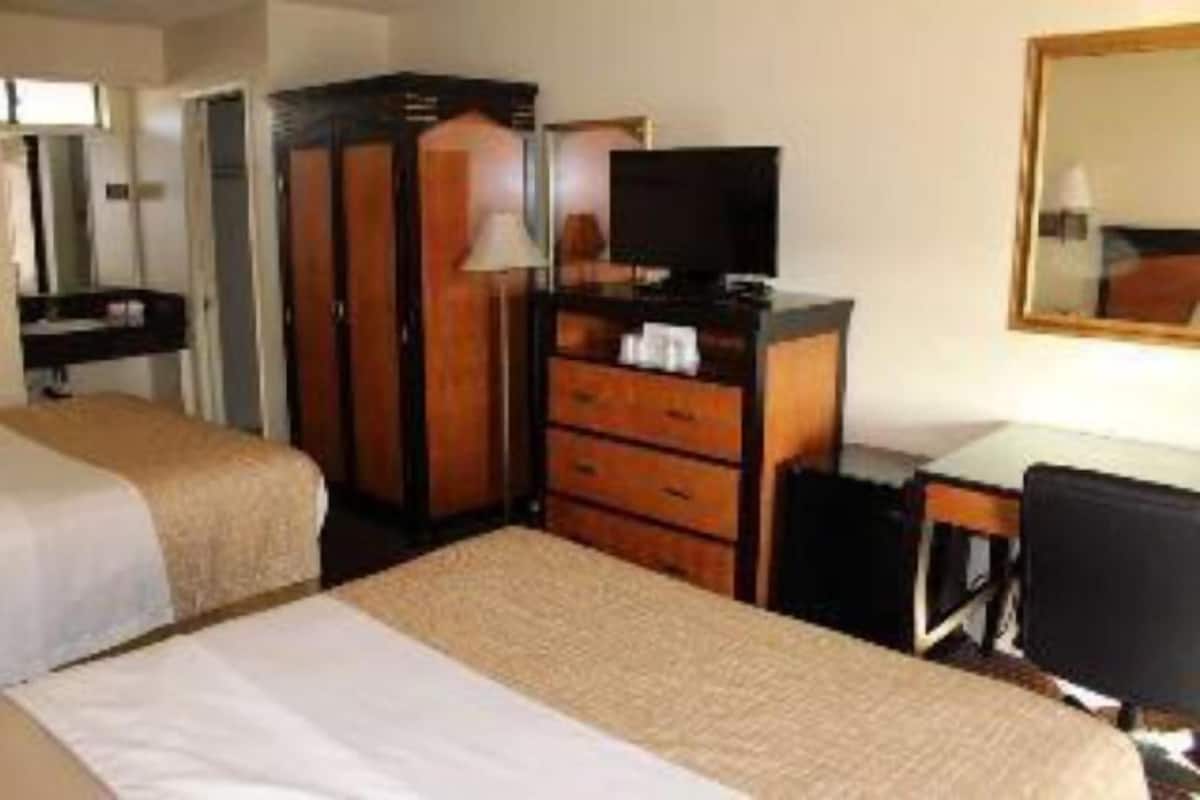 A hotel room with two beds, a desk, a television, and a wardrobe.