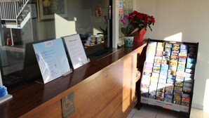 A hotel reception desk with a wooden counter, a sign offering a 5,000 points reward for a free night, and a display of travel brochures. - Travelodge by Wyndham Buena Park (Buena Park)