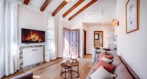 A living room with a fireplace, a television, a sofa, and a dining area.