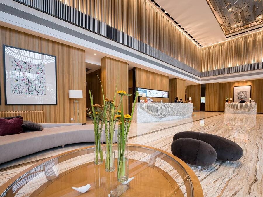 En modern hotellobby med en receptionsdisk, en sittgrupp och en stor, abstrakt målning.