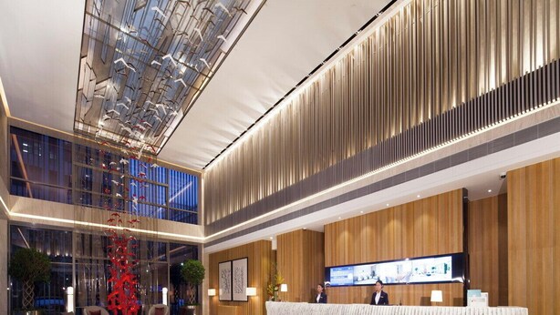 Een moderne hotel lobby met een receptiebalie, een zithoek en een grote glazen koepel.