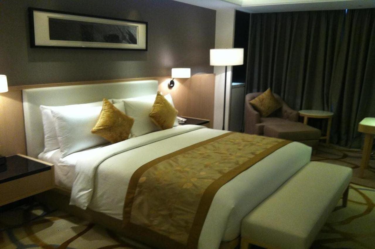 Ein Hotelzimmer mit einem großen Bett, zwei Nachttischen, einem Sessel, einem kleinen Tisch und einer Lampe.