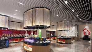 Een moderne hotellobby met een centraal buffetgedeelte, een groot abstracte sculptuur en een gepolijste marmeren vloer.