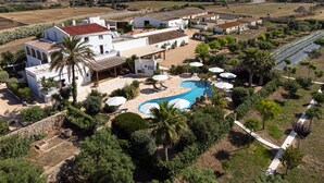 A large villa with a swimming pool, multiple outdoor seating areas, and a well-maintained garden.