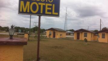 Welcome to the Desoto Motel, a simple motel with single-story buildings surrounded by a grassy area.