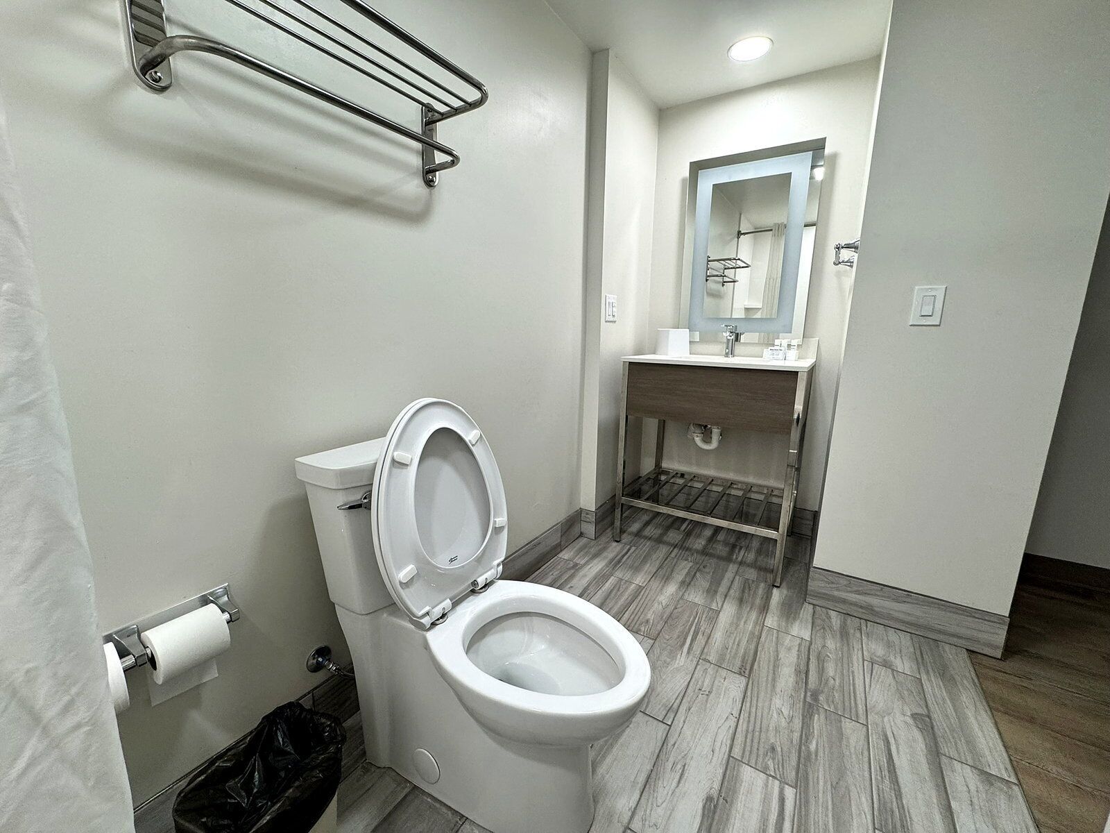 A bathroom with a toilet, a sink, a mirror, and a shower curtain.