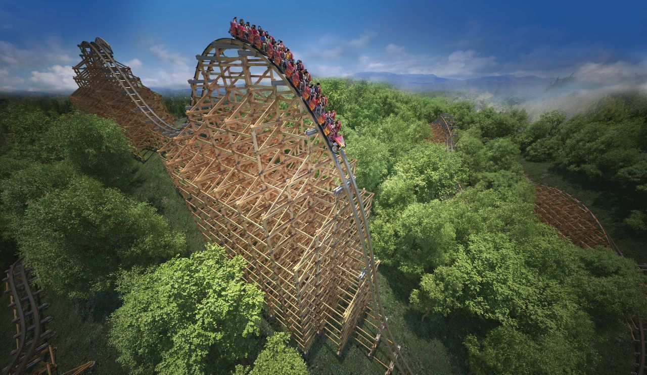 A roller coaster with a wooden structure, surrounded by dense green forest.