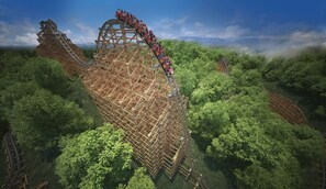 Des montagnes russes à structure en bois, entourées d’une forêt verdoyante et dense.
