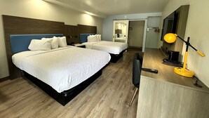 Una habitación de hotel con dos camas, un escritorio, una silla, una lámpara y un televisor.