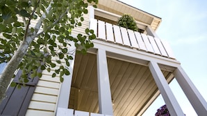 A building with a white exterior, a balcony with a small plant, and a hanging flower basket.