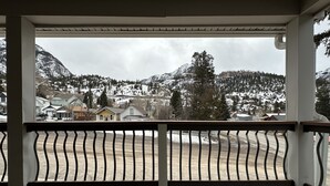 A covered porch with a view of a snowy mountain landscape and residential buildings.