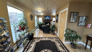 A spacious hallway with a wooden ceiling, a fireplace, and a dining area.