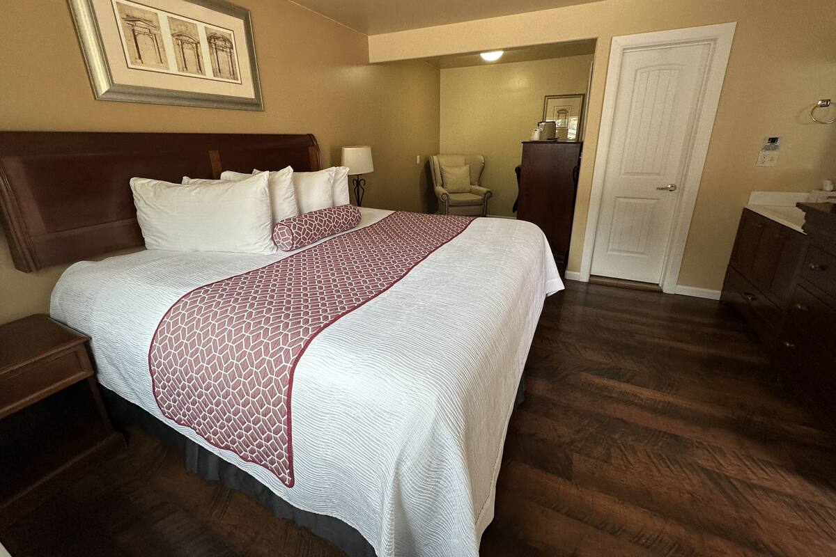 A neatly made bed with a patterned bedspread, a wooden headboard, and a nightstand with a lamp.