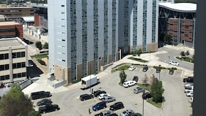 A high-rise building with a modern architectural design, featuring a parking lot with various vehicles and a clear view of the surrounding area. - Residence & Conference Centre - Calgary (Calgary)