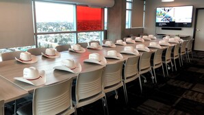 A conference room with a long table set with cowboy hats, large windows with a city view, and a flat-screen TV on the wall. - Residence & Conference Centre - Calgary (Calgary)