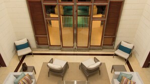 A hotel lobby with a seating area, a large window with shutters, and a view of the interior. - Villa Hall (Gros Islet)