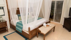 A bedroom with a four-poster bed, a bedside table, a bench, and a tray with breakfast items. - Villa Hall (Gros Islet)