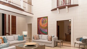A spacious living area with a modern white sofa set, a glass coffee table, and a colorful abstract painting on the wall. - Villa Hall (Gros Islet)
