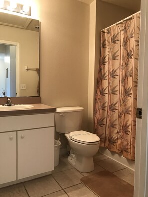 Bathroom features a toilet, sink, and shower with a bamboo leaf patterned curtain.