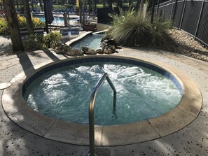 A hot tub with a metal ladder, surrounded by lounge chairs and a pool area. - Freedom Florida Vacation Rentals (Davenport)