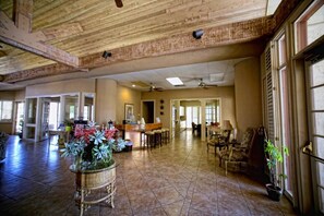 A spacious living area with a high ceiling, a kitchen area with bar stools, and a seating area with chairs and a table. - 4 Seasons at Desert Breezes (Palm Desert)