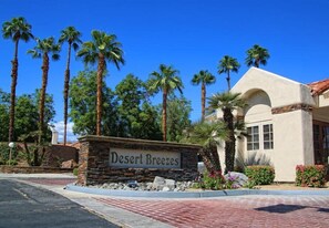A sign reading "Desert Breezes" with palm trees and a building in the background. - 4 Seasons at Desert Breezes (Palm Desert)