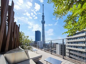 Une terrasse sur le toit offrant une vue sur la tour de Tokyo, un bâtiment moderne et une clôture en treillis métallique.