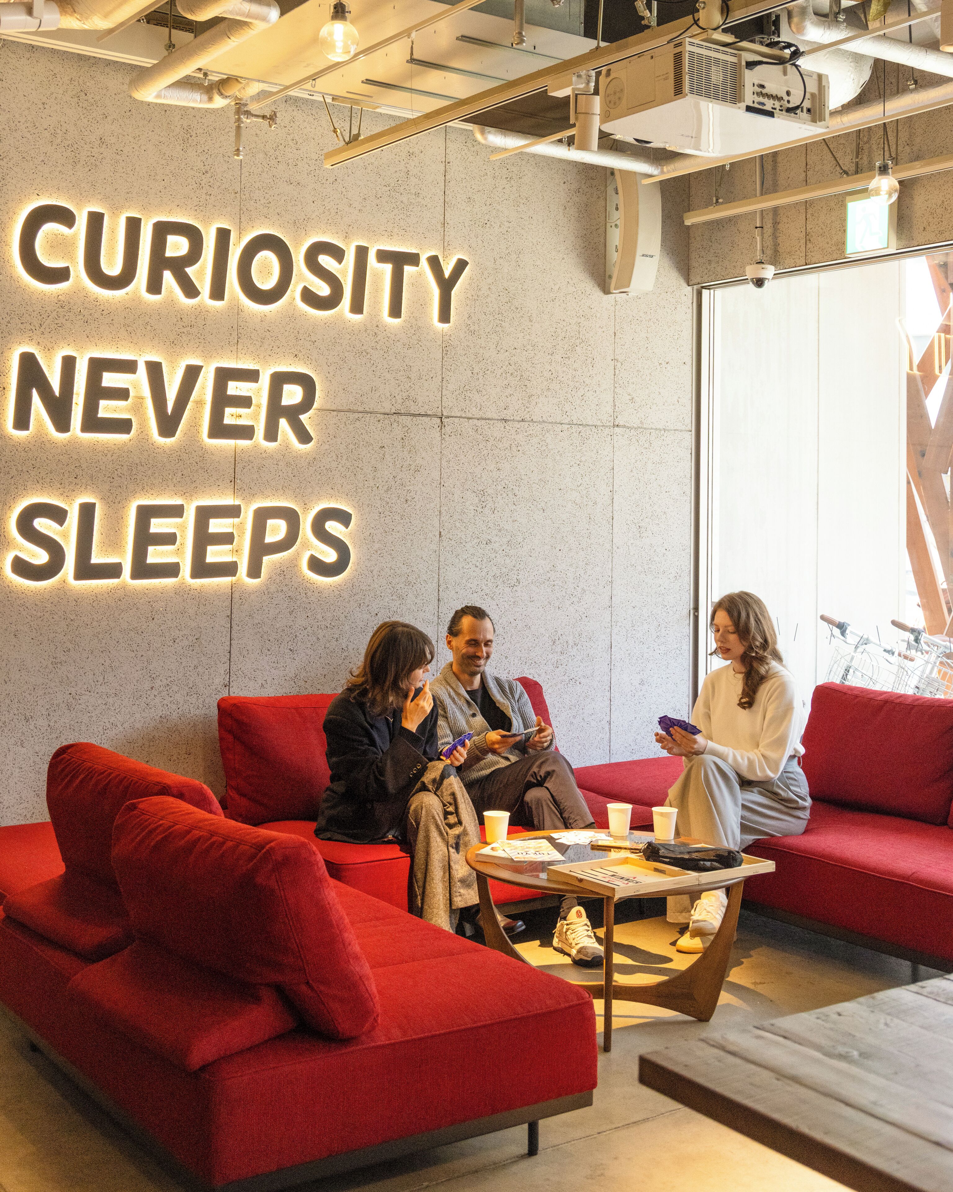 A modern interior with a motivational wall sign, red seating, and a coffee table.