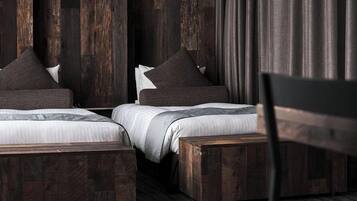 A bedroom with two beds, dark wooden headboards, and a chair.