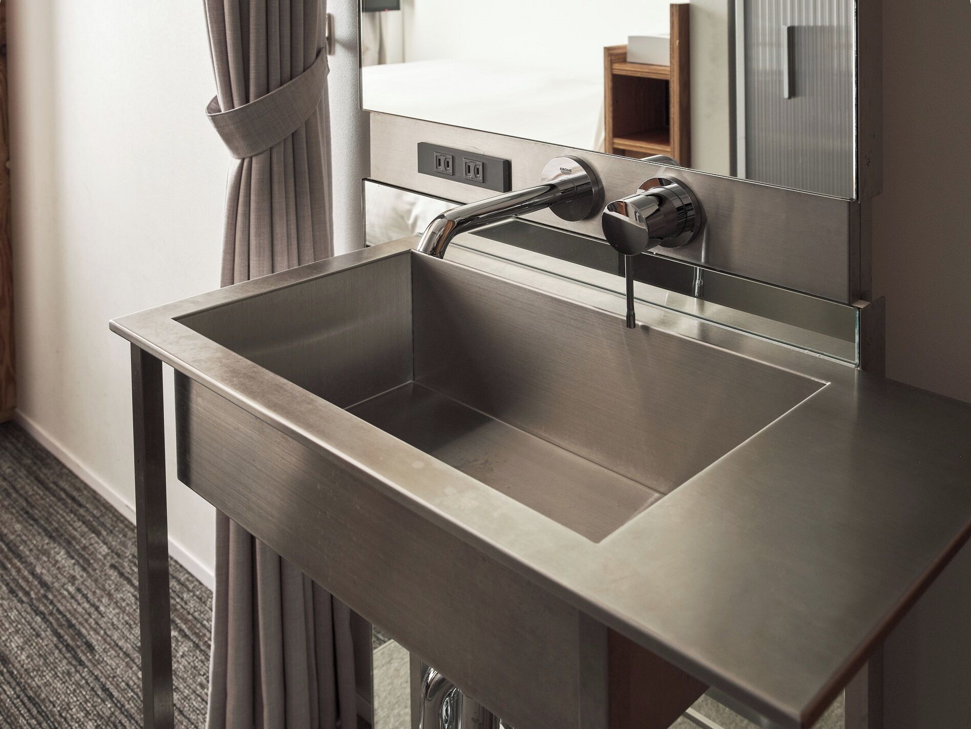A modern bathroom with a stainless steel sink, a mirror, and a towel rack.