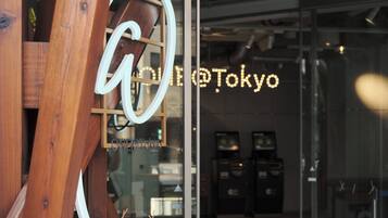 A wooden structure with a neon sign reading 'ONL@Tokyo' and a glass door reflecting interior lighting.