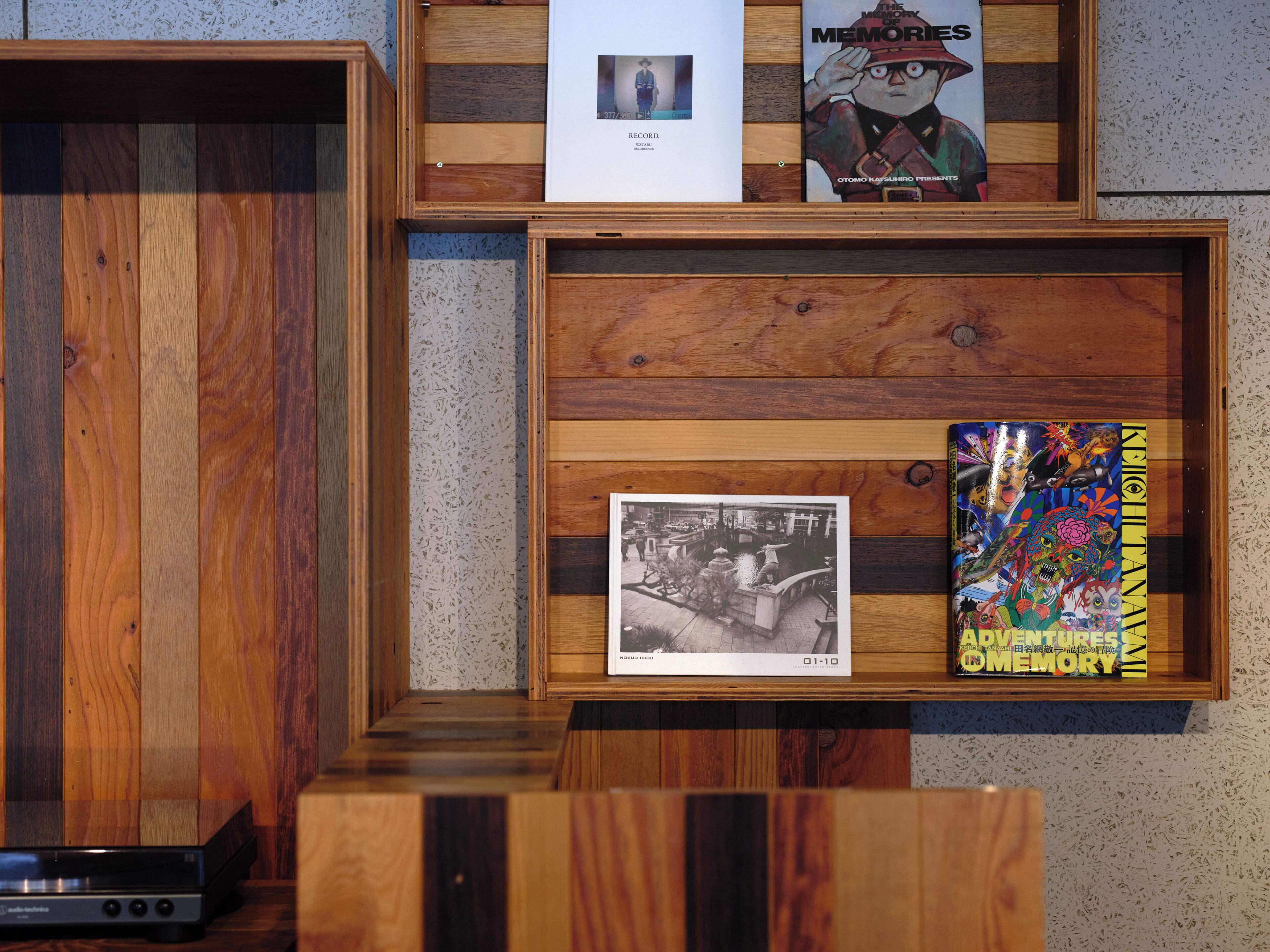 Une exposition d’objets encadrés, comprenant une photographie, un livre et une couverture de livre aux couleurs vives.