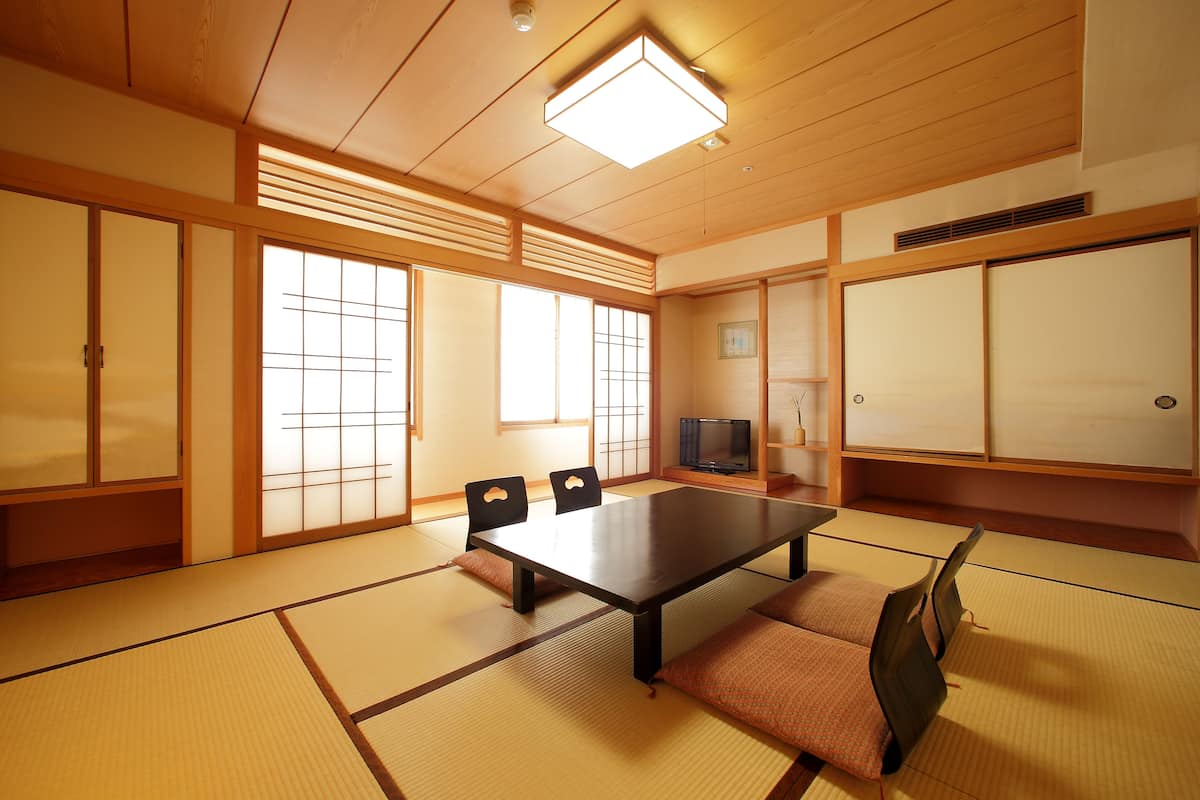 Una habitación japonesa tradicional con suelo de tatami, una mesa baja y puertas correderas.