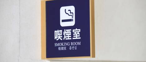 Señal que indica una sala para fumadores, con texto en coreano y traducción al inglés.