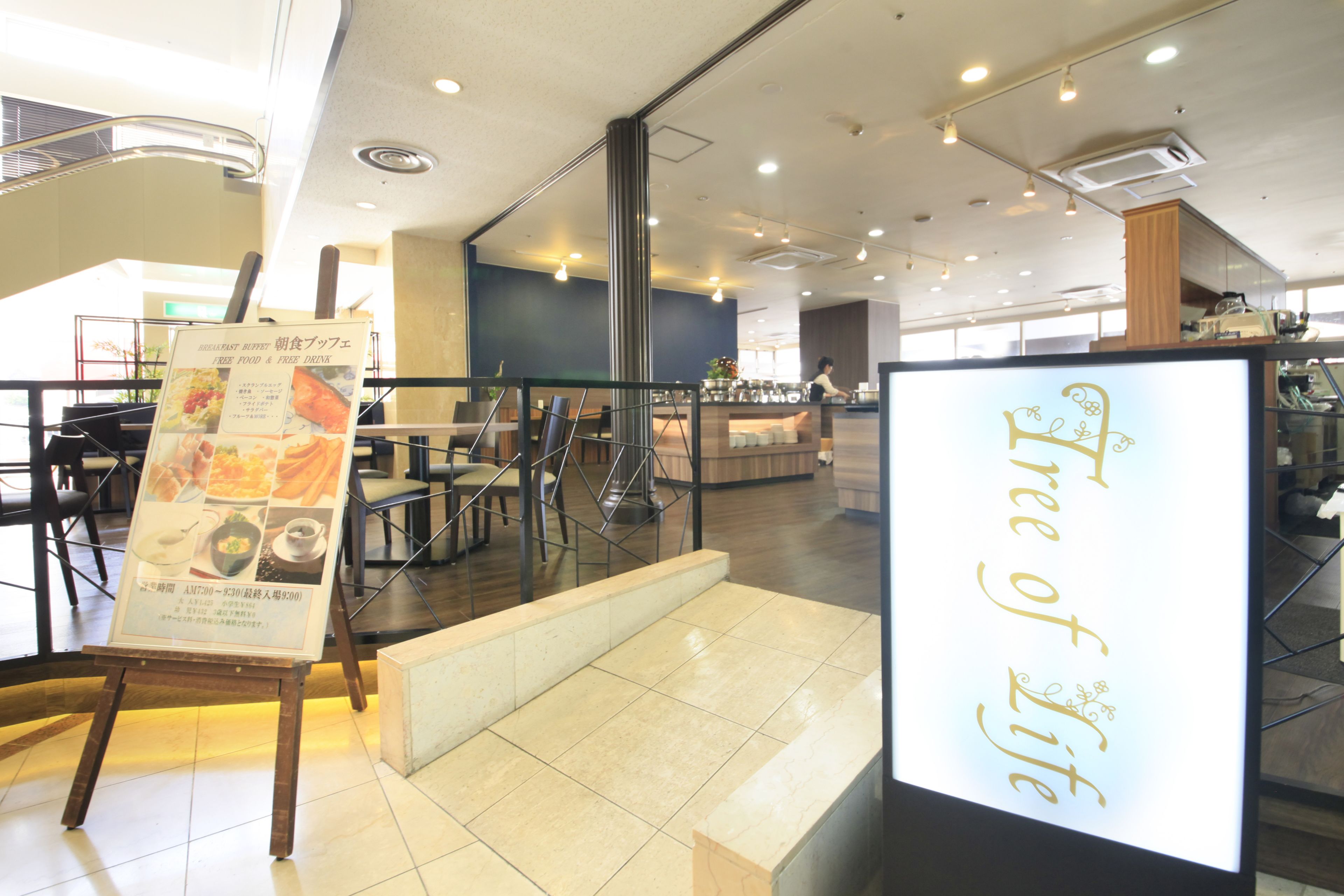 A modern restaurant interior with a high ceiling, tiled floor, and a central counter.