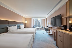 Une chambre d’hôtel avec deux lits, un bureau, une télévision et une vue sur la ville.
