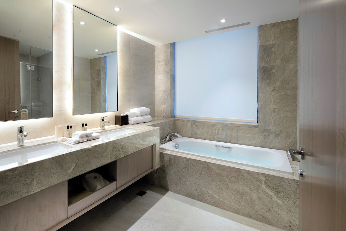 Un baño moderno con un espejo grande, una bañera y un tocador con lavabo.