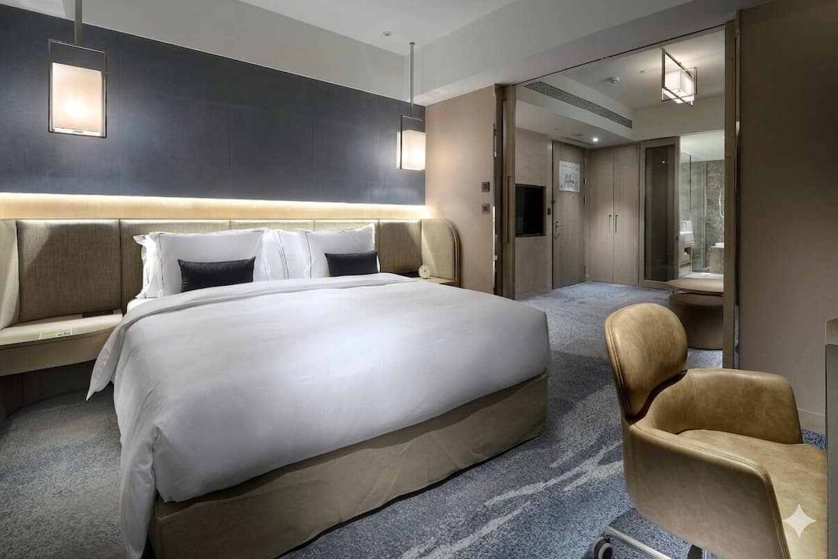 Quarto de hotel com uma cama grande, mesa de cabeceira, cadeira, espelho e guarda-roupa.