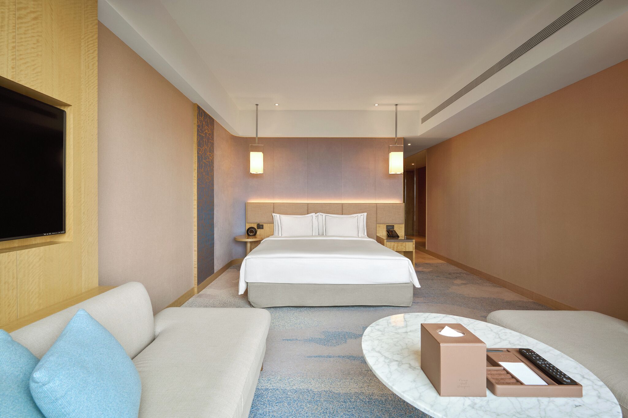A hotel room with a bed, a sofa, a TV, a bedside table, and a nightstand.