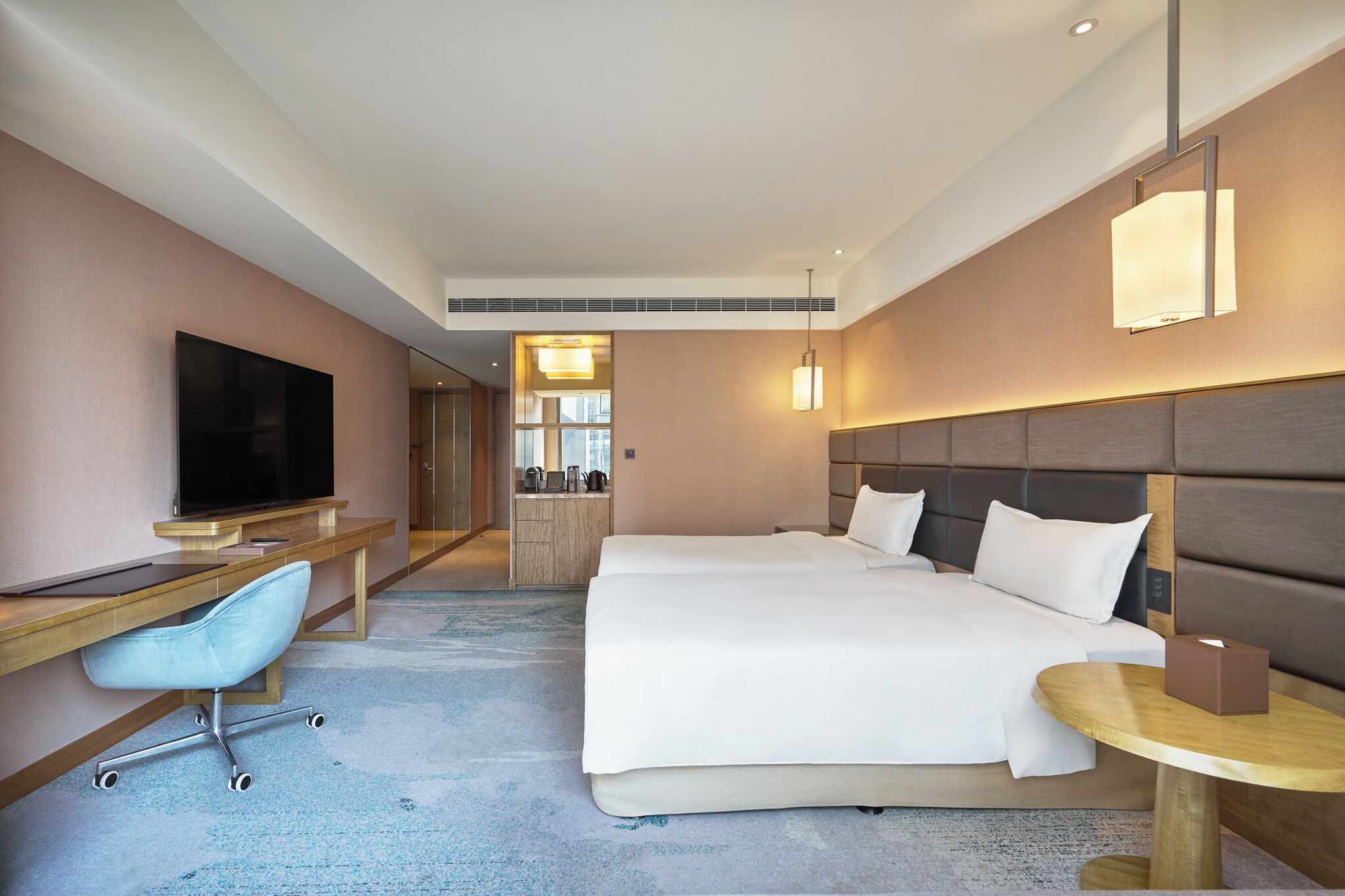 Habitació d'hotel amb llit, escriptori, cadira, televisió i una taula petita amb una caixa.